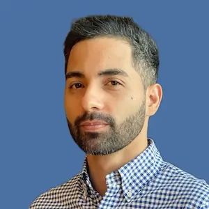 Robert Abreu wearing a long sleeve polo with small box pattern on a blue background.